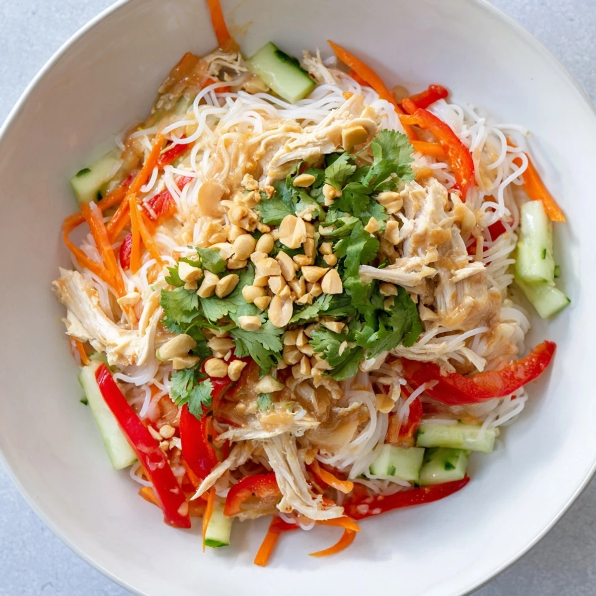 This vibrantly plated Thai-Inspired Peanut Chicken Pasta shows tossed noodles, shredded chicken, and fresh garnishes.