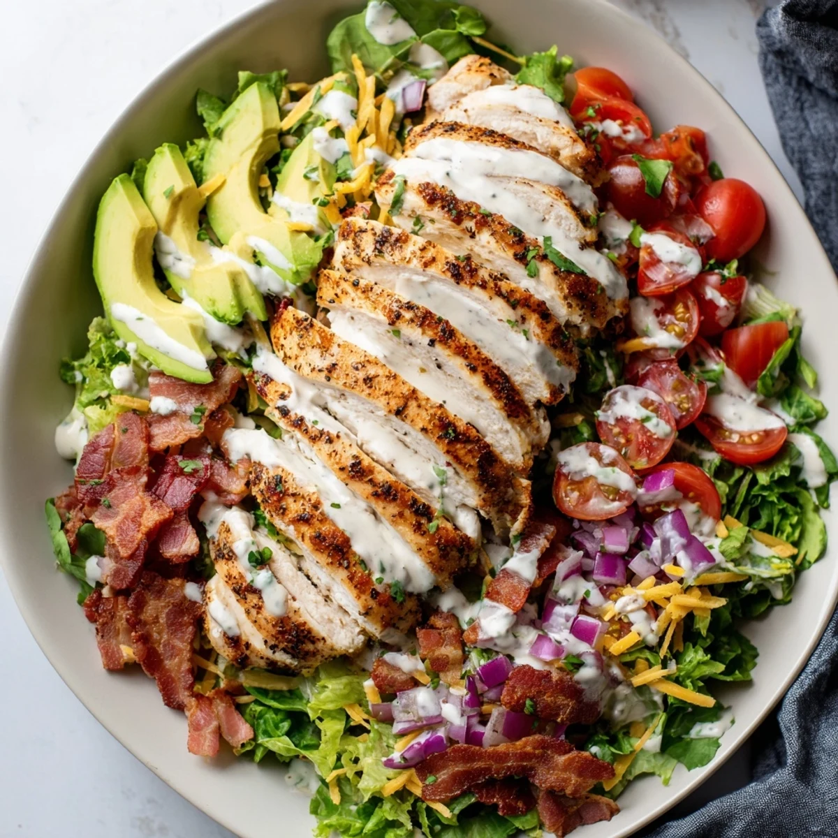 Enjoy a colorful bowl, showcasing a delectable Crispy Bacon Chicken Salad with ranch dressing.