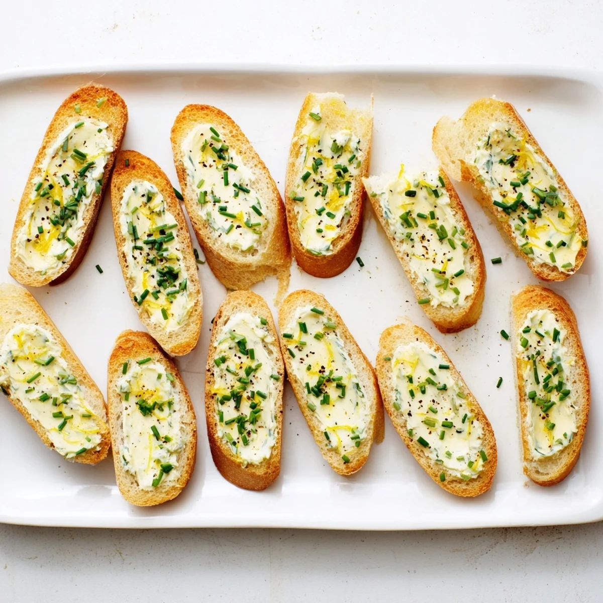 Golden, crisp vodka butter crostini topped with fresh chives and lemon zest, served as an elegant appetizer for cocktail parties.  