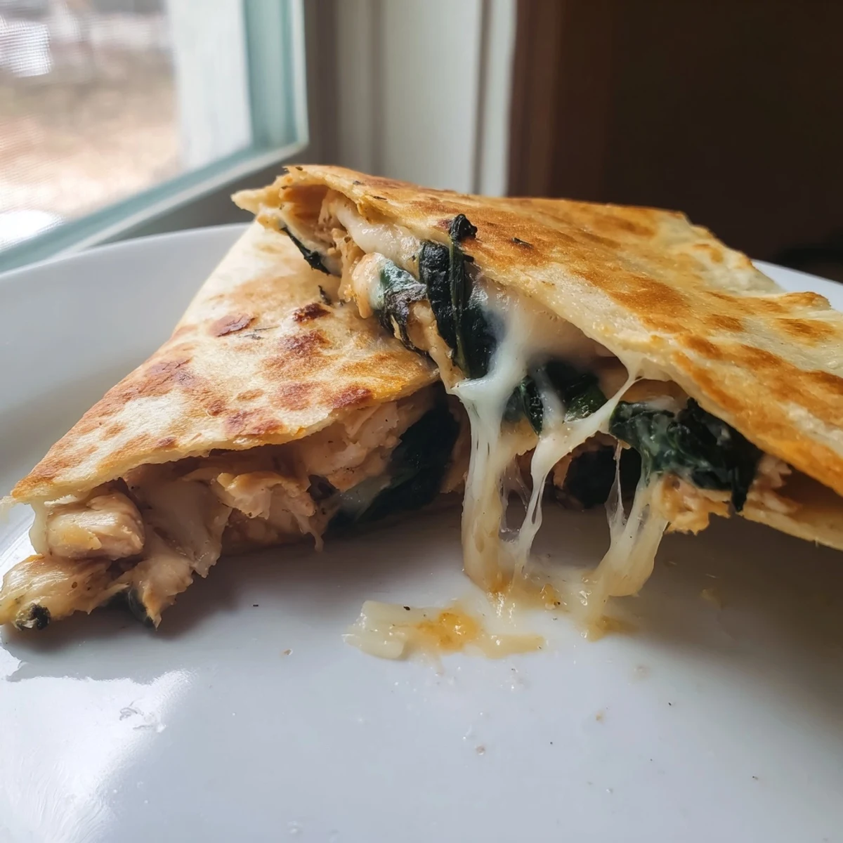 Golden-brown Chicken and Spinach Quesadilla wedges are served warm with melted mozzarella peeking out.