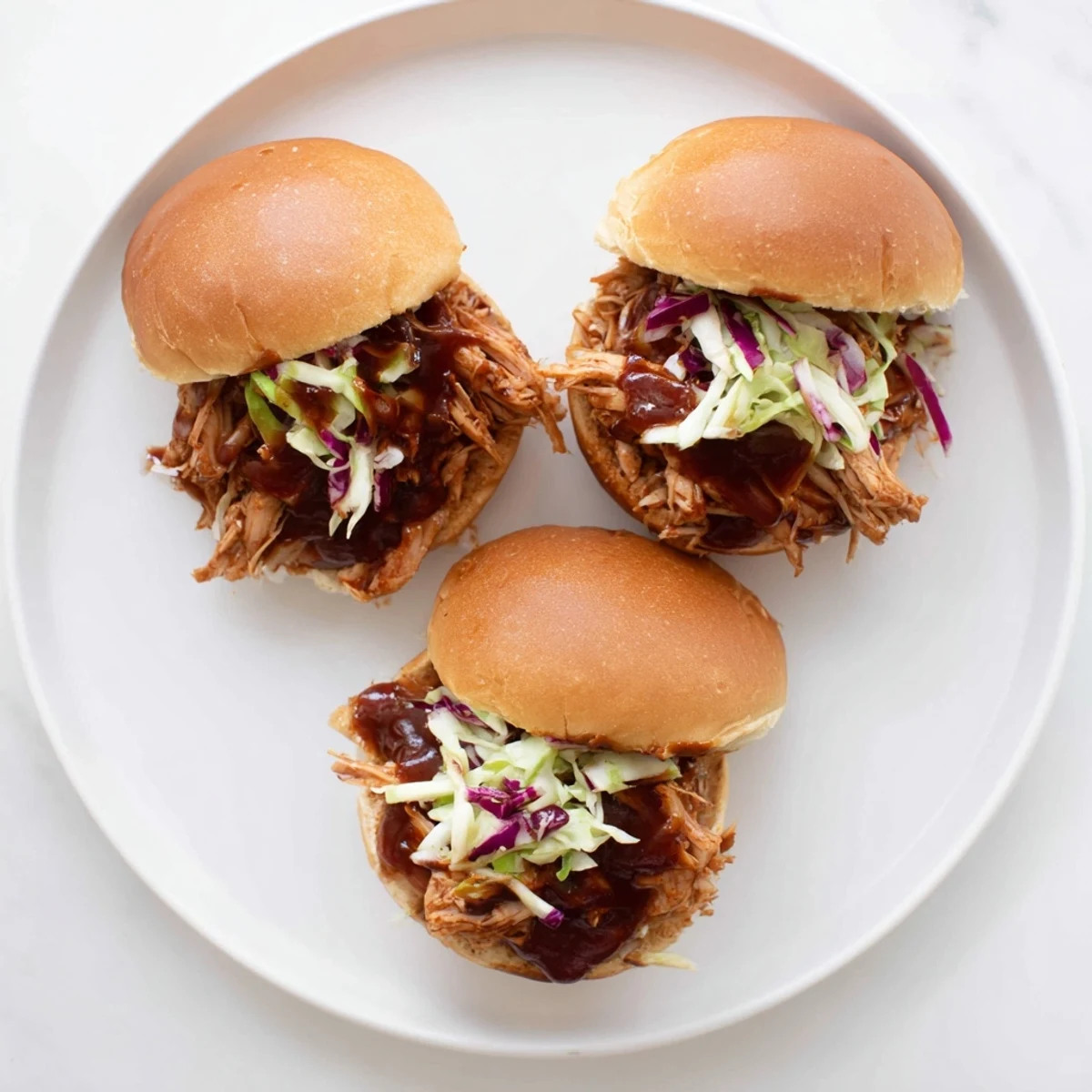 Tender BBQ chicken and vibrant slaw stuffed in soft slider buns for a party appetizer.