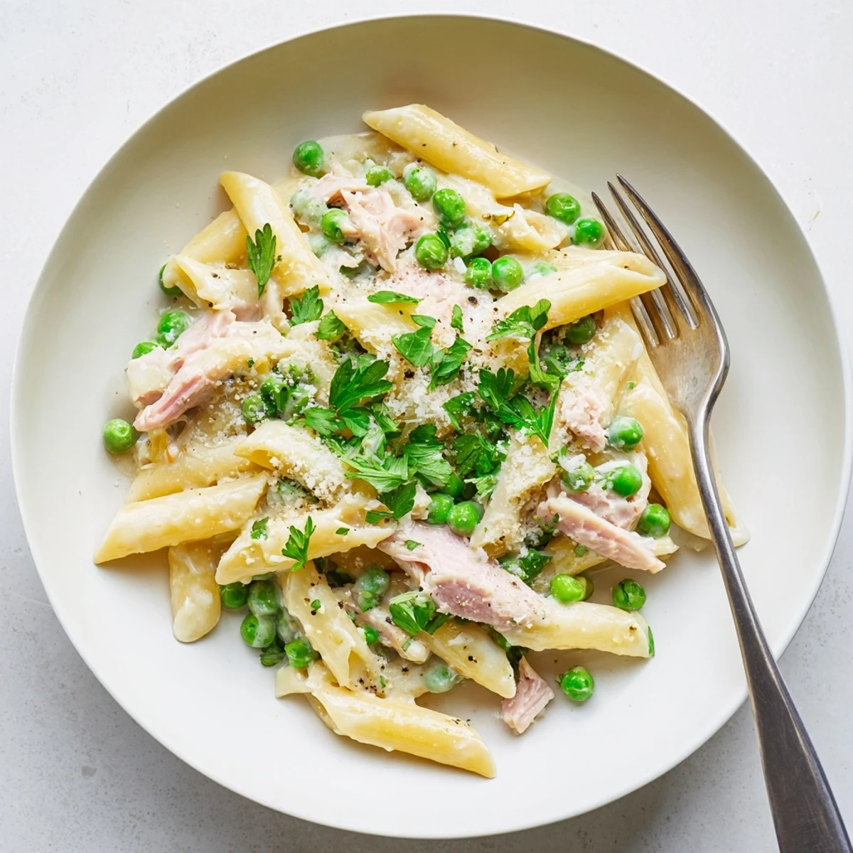 Tossing penne in a creamy sauce, this Spring Pea & Ham Pasta is topped with fresh parsley and grated Parmesan.