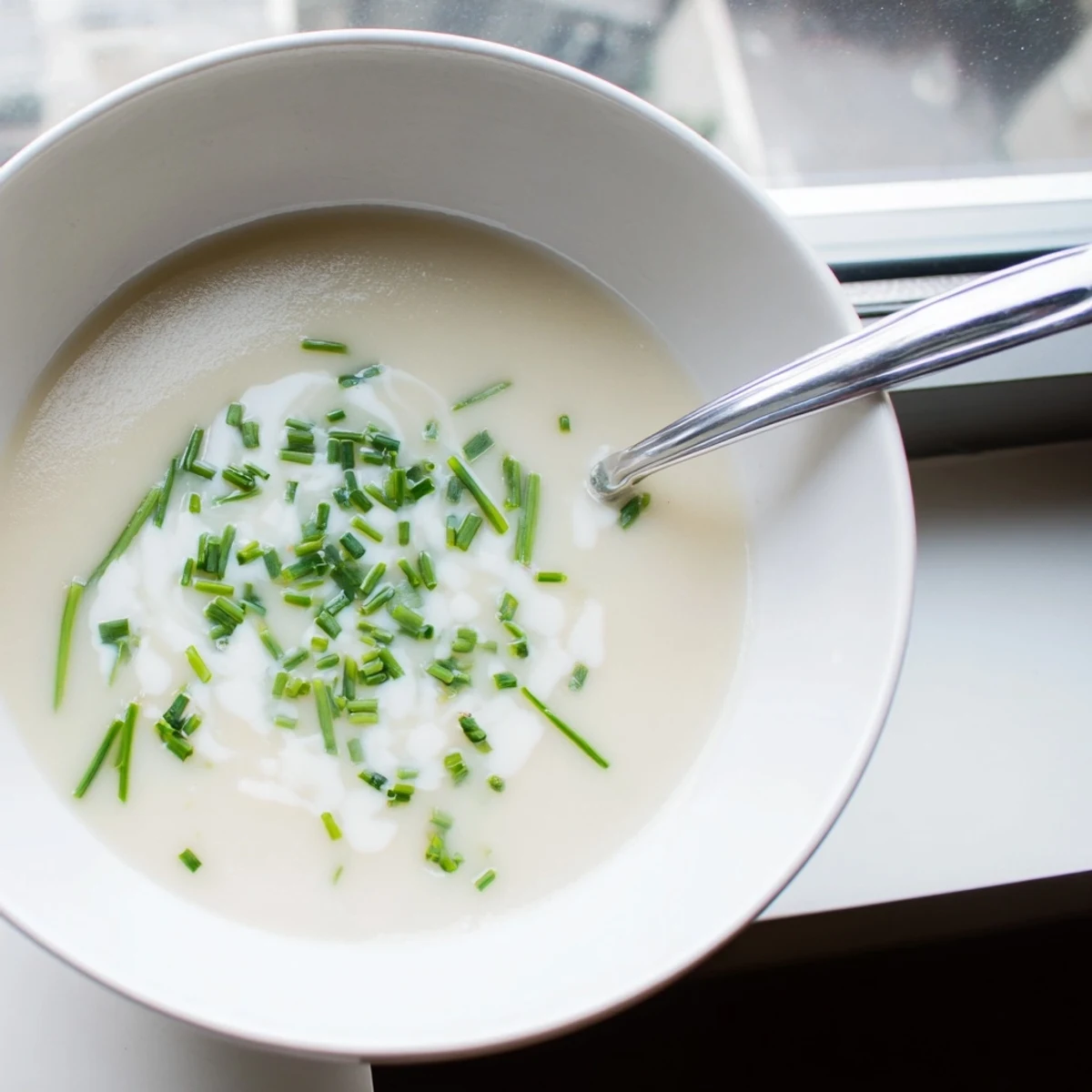 A bowl of velvety celery root bisque, steaming gently next to a slice of rustic crusty bread.