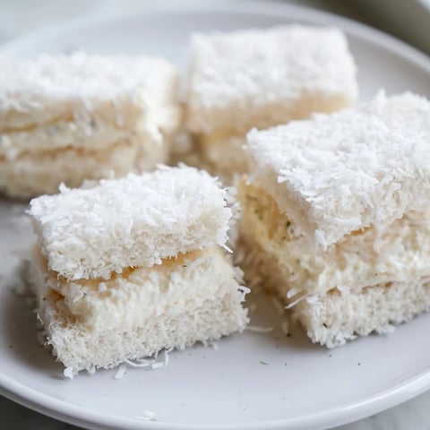 Snowball Tea Sandwich Bites, white bread rounds covered in coconut, ready for a winter treat.