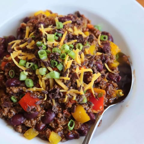 Close-up of rich One-Pot Cozy Chocolate Chili with visible beans, beef, and cocoa nibs.
