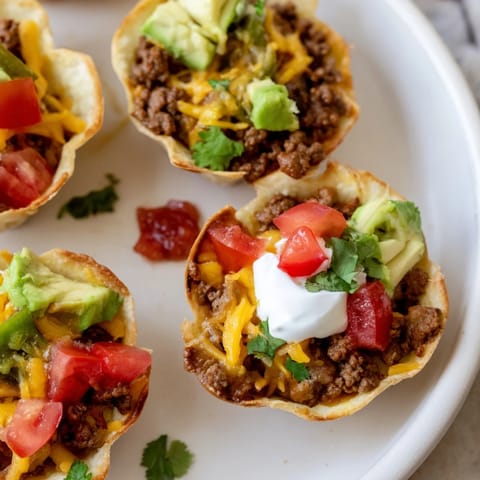 Warm, crispy-edged Mini Taco Cups overflowing with melted cheese and savory ground beef filling.