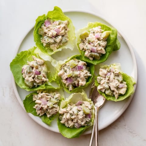 Bright green lettuce cradles zesty dill pickle chicken salad, showcasing chopped pickles, red onion, celery, and fresh dill for a refreshing, crunchy bite.