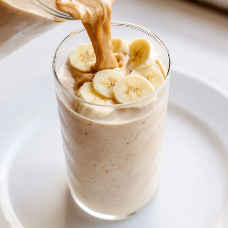 This refreshing Peanut Butter Banana Smoothie features a vibrant yellow hue, hinting at ripe sweetness.
