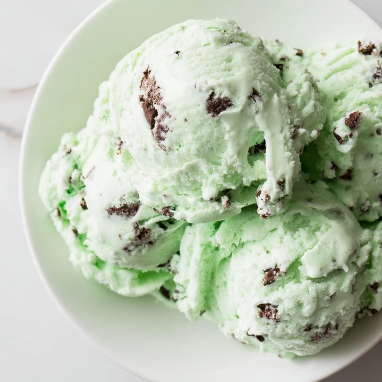 Creamy, green-tinted mint chocolate chip ice cream, speckled with mini chocolate chip pieces.